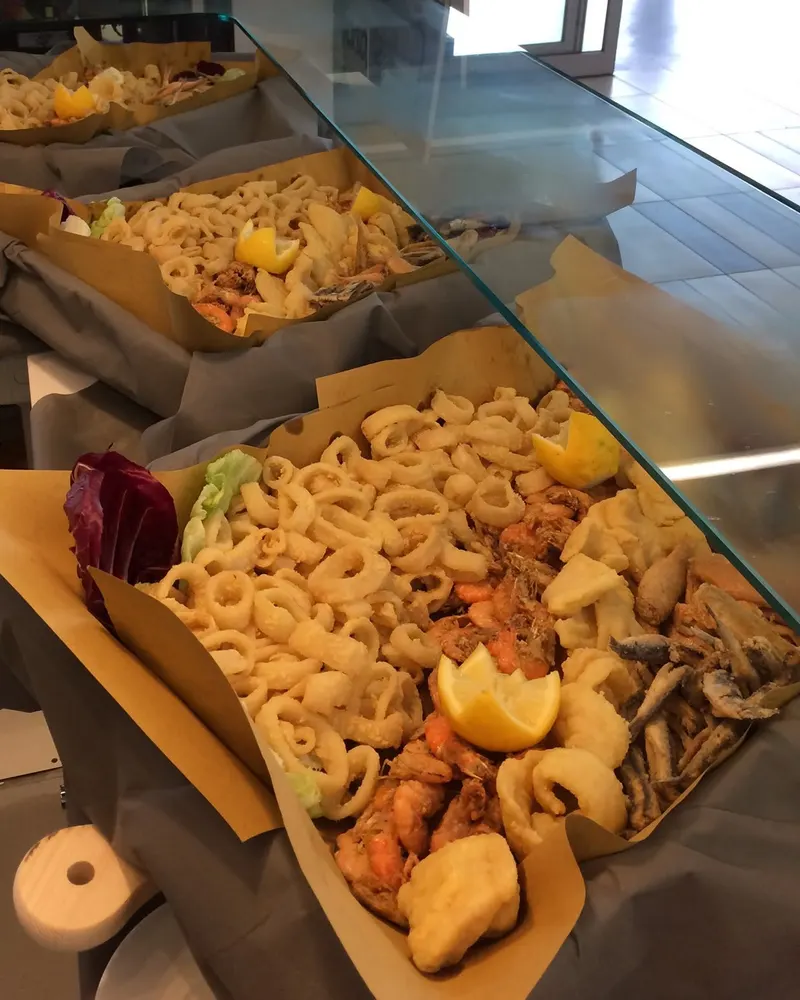 Vassoi di fritto misto di mare su carta paglia al banco di Gustò 24